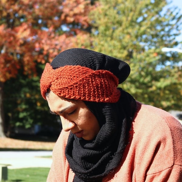 Woman wearing a stylish crochet headband. Spice Swirl Tunisian Crochet Twist Headband Pattern by Noor’s Knits